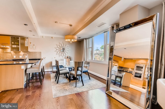 dining area featuring visible vents, baseboards, wood finished floors, and crown molding