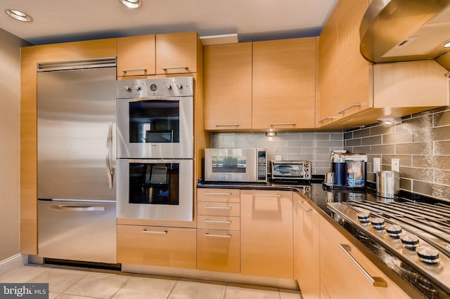 kitchen featuring light tile patterned floors, decorative backsplash, appliances with stainless steel finishes, and a toaster