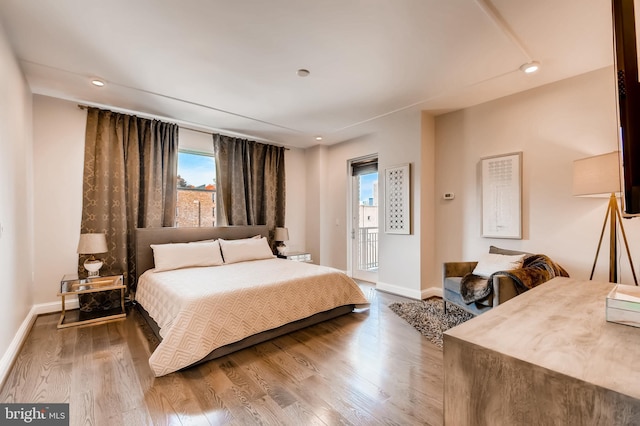 bedroom with access to outside, recessed lighting, wood finished floors, and baseboards