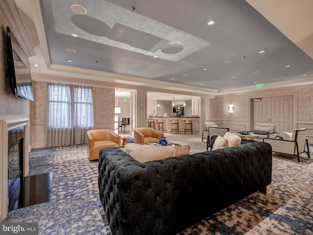 living area with a tray ceiling, ornamental molding, carpet flooring, a fireplace, and a decorative wall