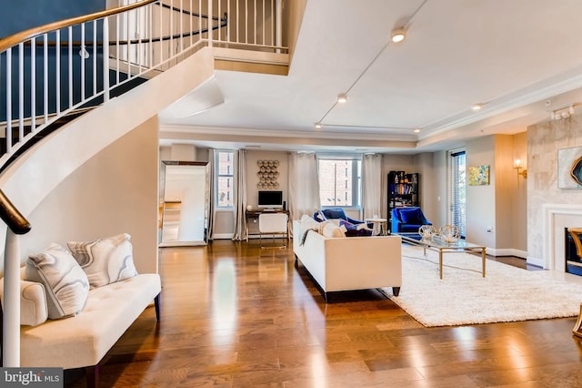 living area with baseboards, stairs, a premium fireplace, ornamental molding, and wood finished floors