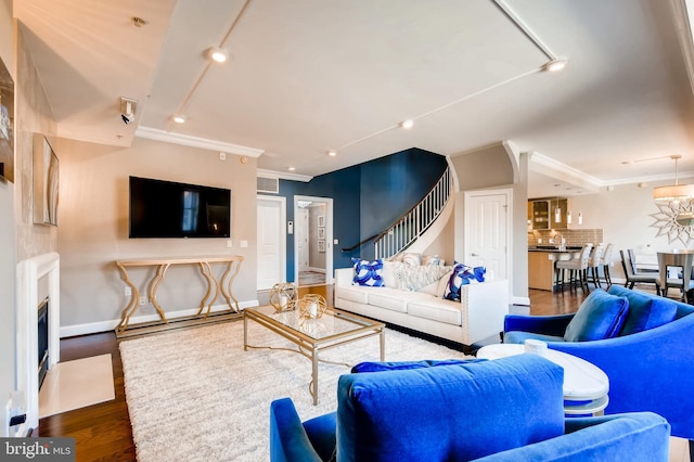 living room with a fireplace with flush hearth, wood finished floors, baseboards, and ornamental molding