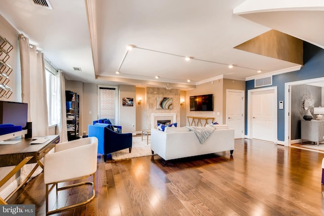 living room with wood finished floors, a fireplace, visible vents, and baseboards