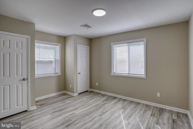 unfurnished bedroom featuring multiple windows and light hardwood / wood-style floors