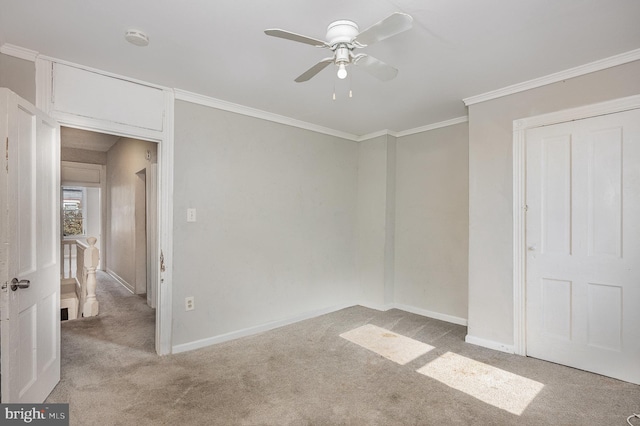 empty room with crown molding, light carpet, and ceiling fan