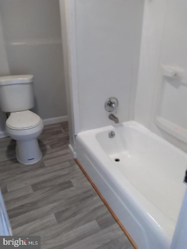 bathroom featuring hardwood / wood-style flooring, toilet, and bathing tub / shower combination