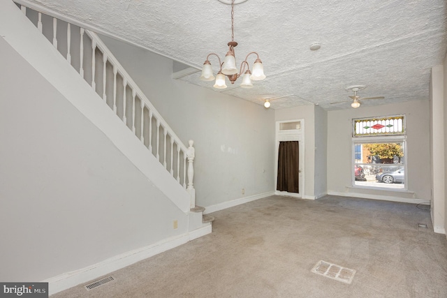 entryway with a textured ceiling, carpet floors, and ceiling fan with notable chandelier