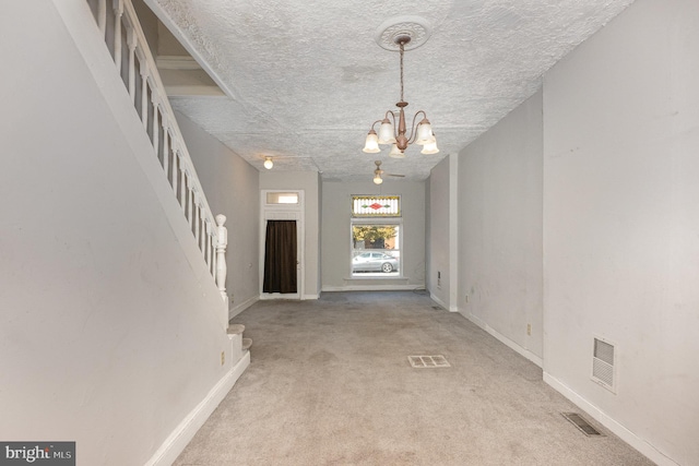 carpeted foyer featuring a textured ceiling and an inviting chandelier