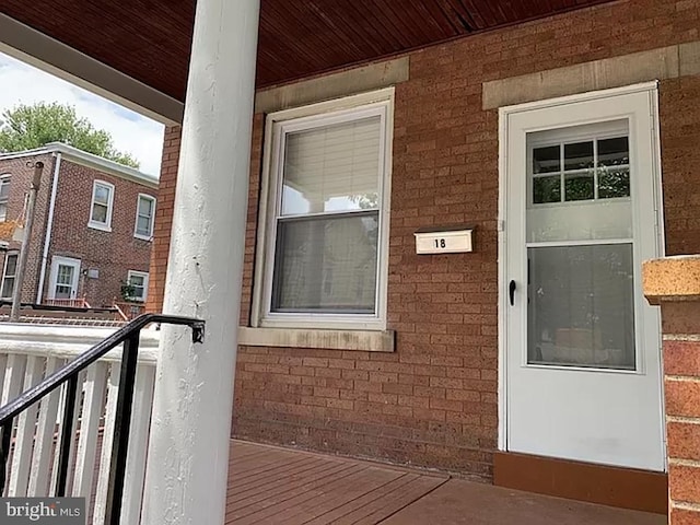 property entrance with brick siding and a balcony