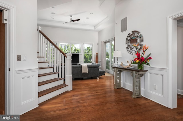 entrance foyer featuring a wainscoted wall, visible vents, a decorative wall, wood finished floors, and stairs