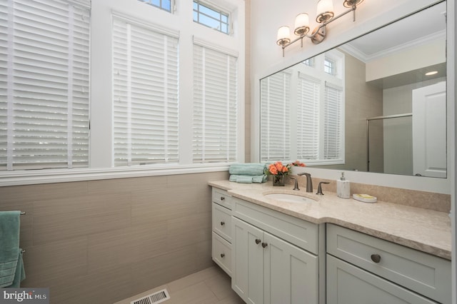 full bathroom with vanity, ornamental molding, a shower stall, and visible vents