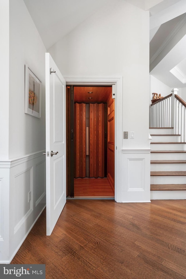 hall with wood finished floors, wainscoting, vaulted ceiling, and stairs