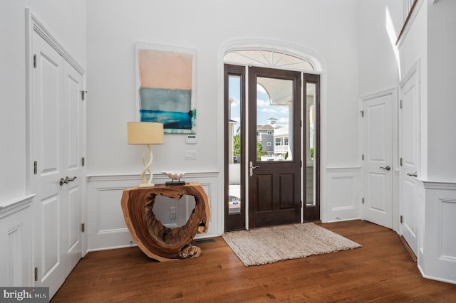 foyer entrance featuring a decorative wall, wood finished floors, and wainscoting