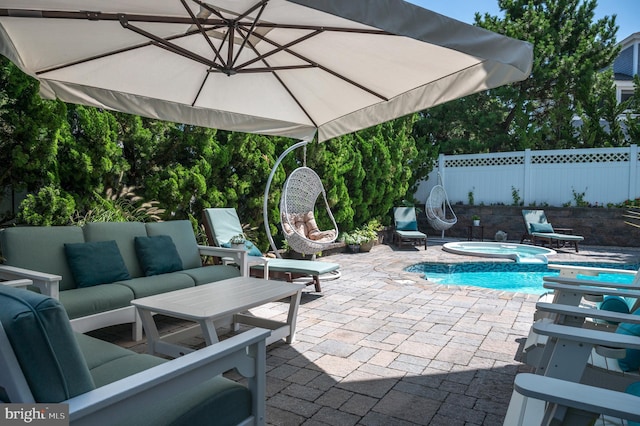 view of patio with outdoor lounge area, fence, and an in ground hot tub