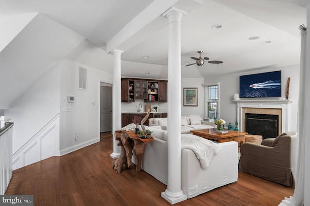 living room featuring decorative columns, visible vents, a ceiling fan, a premium fireplace, and wood finished floors