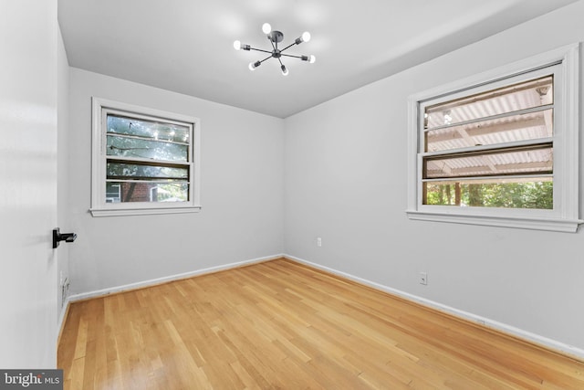 unfurnished room with light wood-type flooring and a chandelier