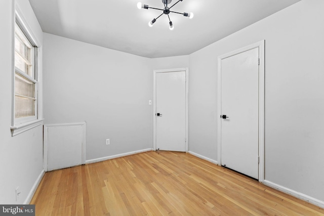 unfurnished bedroom with light hardwood / wood-style flooring and a notable chandelier