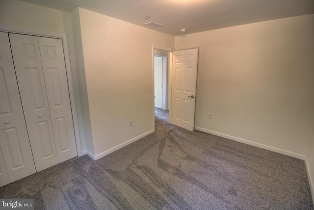 unfurnished bedroom featuring dark colored carpet and a closet