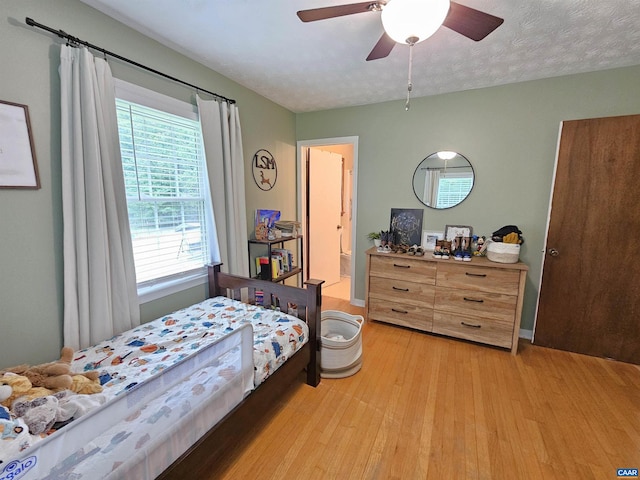 bedroom featuring ceiling fan, light hardwood / wood-style floors, and a textured ceiling