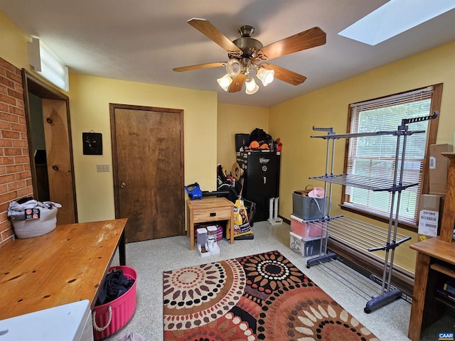 carpeted office featuring a skylight and ceiling fan