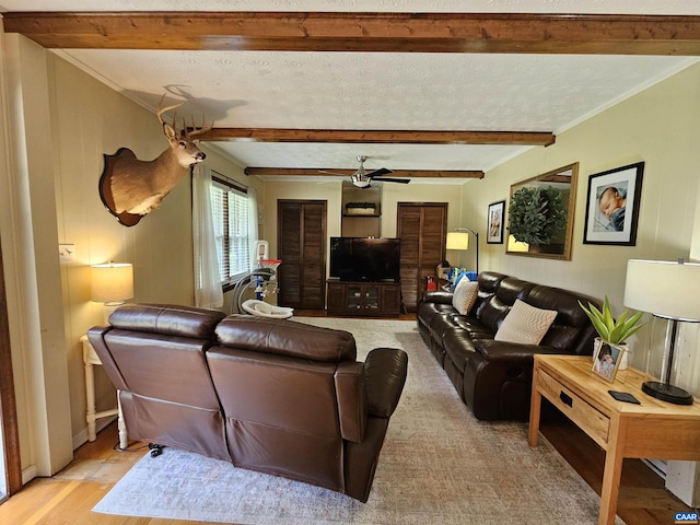 living room featuring a textured ceiling, ceiling fan, beamed ceiling, and light wood-type flooring