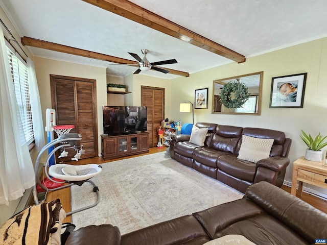 living room with a wealth of natural light, ceiling fan, wood-type flooring, and beam ceiling