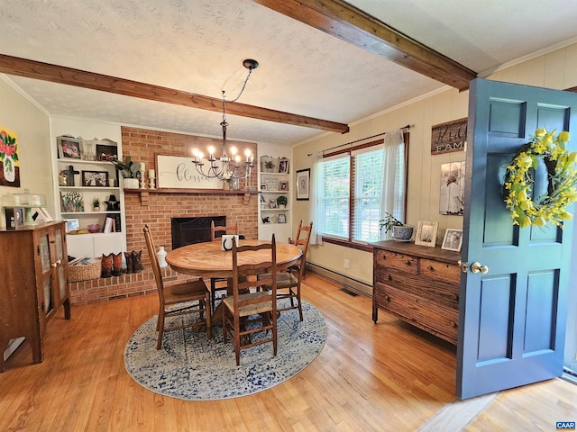 dining space featuring a textured ceiling, a chandelier, a brick fireplace, beam ceiling, and light hardwood / wood-style floors