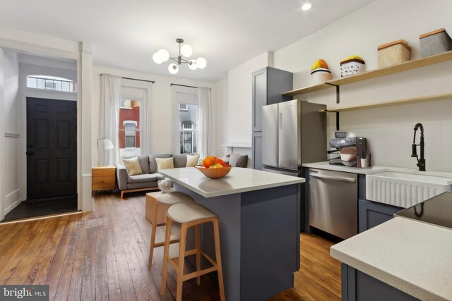 kitchen featuring dark hardwood / wood-style floors, a notable chandelier, a center island, stainless steel appliances, and sink