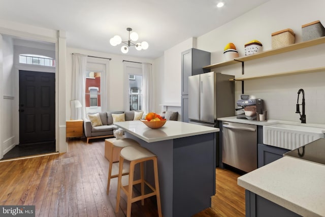 kitchen featuring a sink, open shelves, hardwood / wood-style floors, and stainless steel appliances