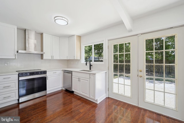 kitchen with sink, white cabinetry, stainless steel appliances, beam ceiling, and wall chimney range hood