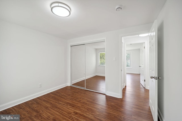 unfurnished bedroom with dark wood-type flooring and a closet