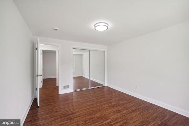 unfurnished bedroom with dark wood-type flooring and a closet