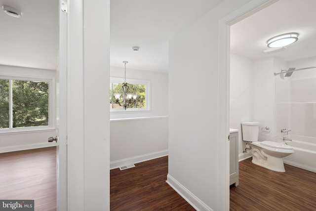 full bathroom featuring toilet, an inviting chandelier,  shower combination, vanity, and hardwood / wood-style floors