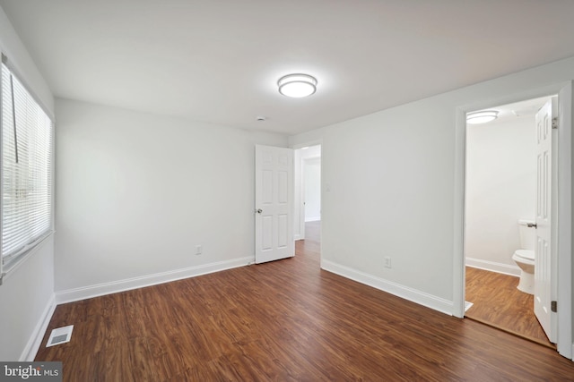 unfurnished bedroom featuring dark hardwood / wood-style flooring and ensuite bath