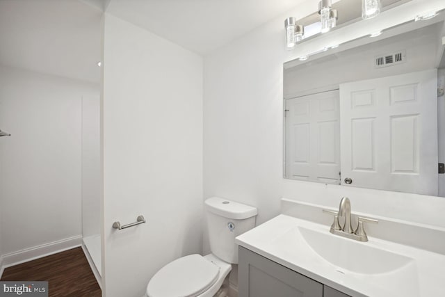 bathroom featuring vanity, wood-type flooring, and toilet