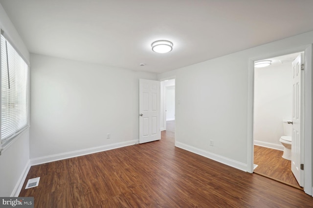 unfurnished bedroom featuring dark wood-type flooring and connected bathroom