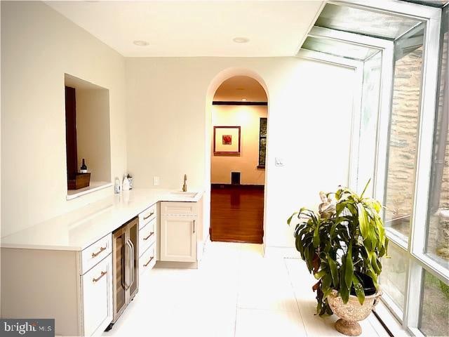 interior space with light tile patterned floors, wine cooler, and sink