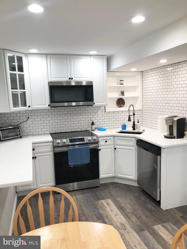 kitchen with white cabinets, appliances with stainless steel finishes, sink, dark hardwood / wood-style floors, and decorative backsplash