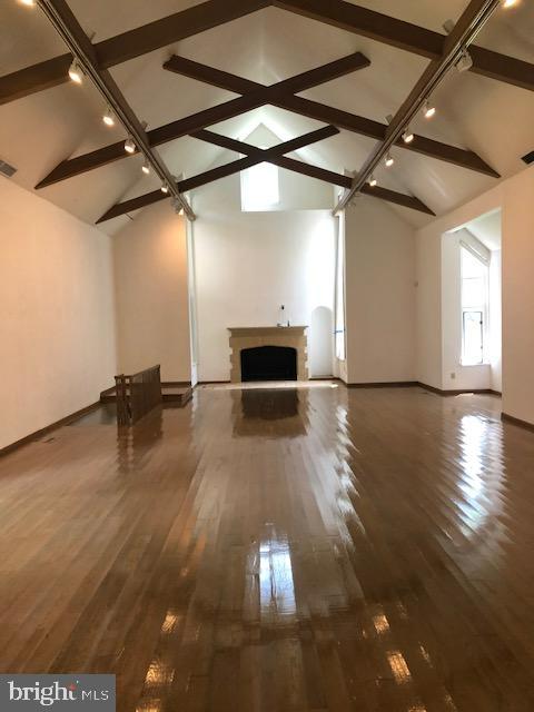 unfurnished living room featuring lofted ceiling with beams and dark hardwood / wood-style flooring