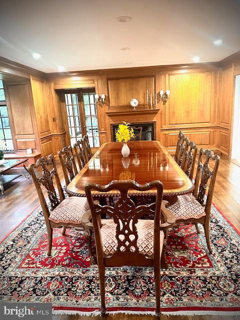 dining room featuring hardwood / wood-style flooring, wood walls, and a wealth of natural light