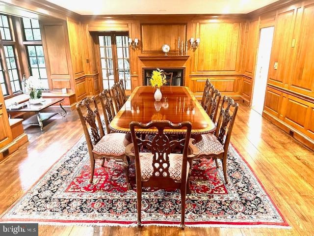 dining room with light wood-type flooring, wood walls, and french doors