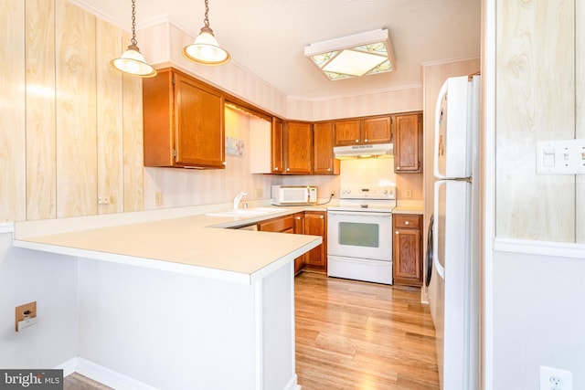 kitchen featuring under cabinet range hood, light wood-type flooring, brown cabinets, a peninsula, and white appliances