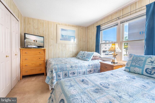 bedroom featuring a textured ceiling, carpet, wood walls, and a closet