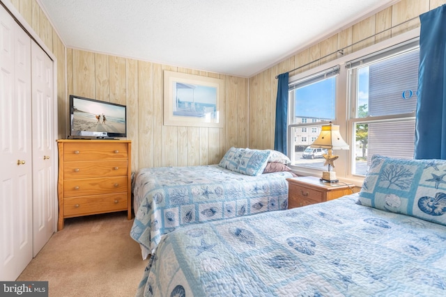 bedroom with a closet, carpet, wood walls, and a textured ceiling