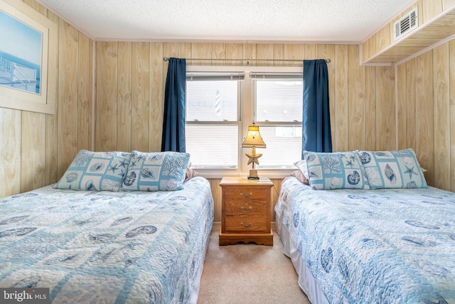 bedroom with visible vents, wood walls, a textured ceiling, and carpet