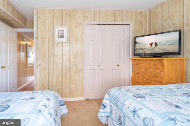 bedroom featuring a closet, a textured ceiling, wooden walls, and carpet