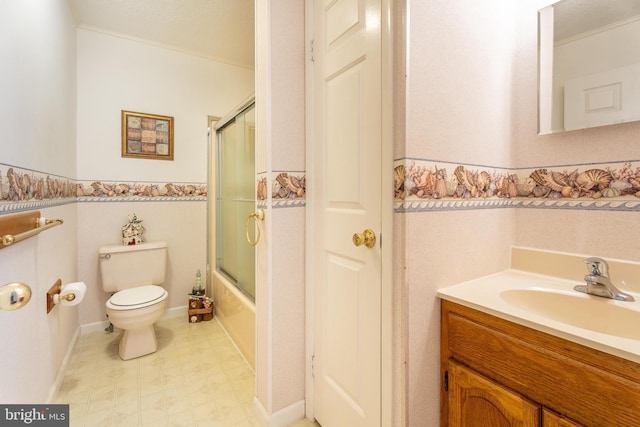 bathroom with vanity, wainscoting, tile patterned floors, toilet, and combined bath / shower with glass door