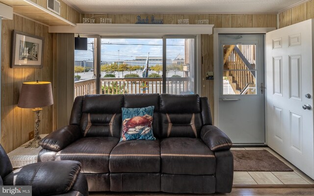 living room with a healthy amount of sunlight, wood walls, and light hardwood / wood-style flooring