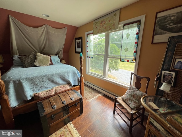 bedroom with vaulted ceiling, a baseboard heating unit, and wood finished floors