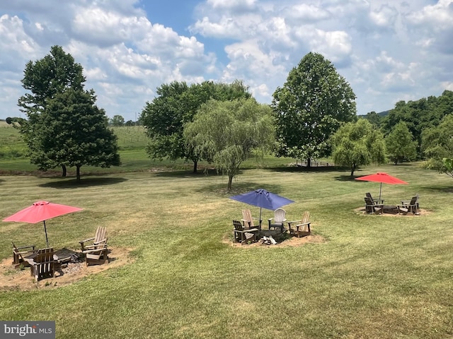 view of property's community with a lawn and an outdoor fire pit